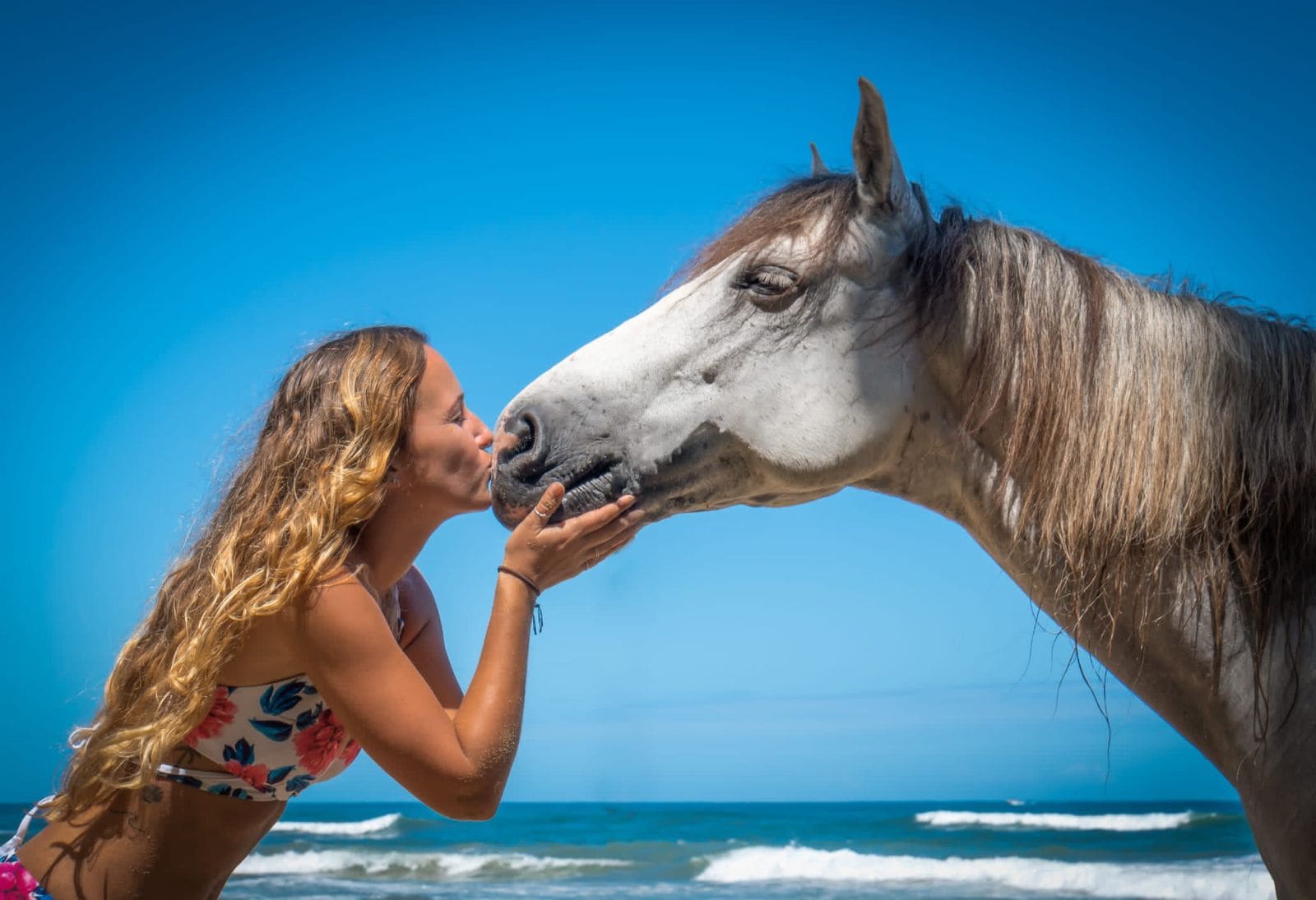 A woman shares a moment nose-to-nose with a horse on the beach in Cocles, the Caribbean Sea behind them